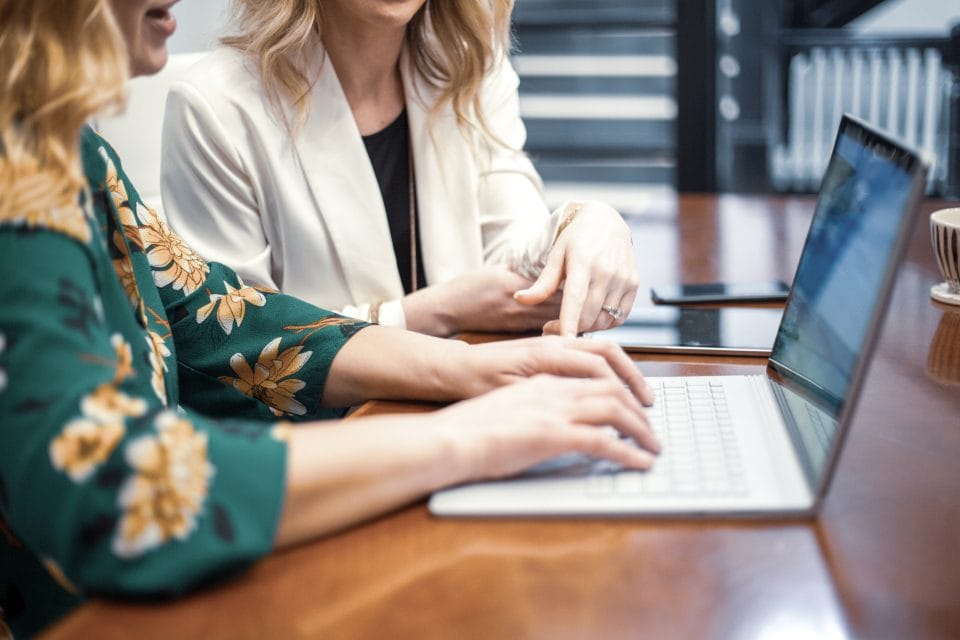 Zwei Personen betrachten gemeinsam eine Website auf einem Laptop